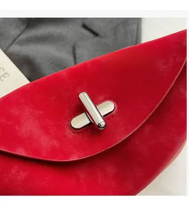 Detailed macro view of red suede handbag featuring a silver metallic twist lock closure
