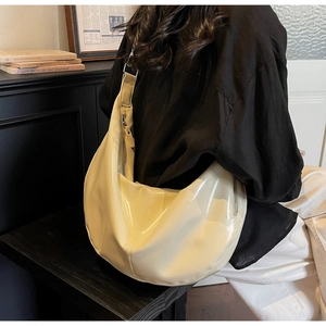 Chic cream patent leather hobo bag worn by a model in a sophisticated setting