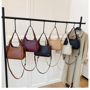 Vue détaillée de sacs hobo tissés en plusieurs couleurs suspendus à un support métal