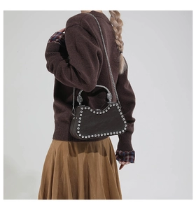 Close-up of vintage gothic brown leather bag with silver studs and embossed metal handle