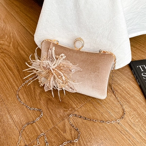 Elegant velvet clutch bag with 3D floral decoration and gold chain strap in a warm setting