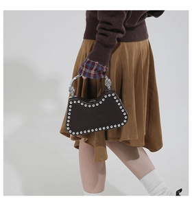 Detail of dark brown leather box bag with silver rivets and twisted metal handle