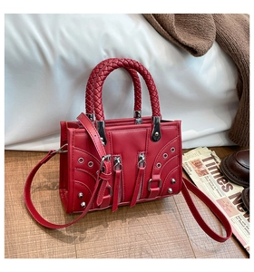 Detail of red biker style handbag featuring metallic zippers and woven handle design