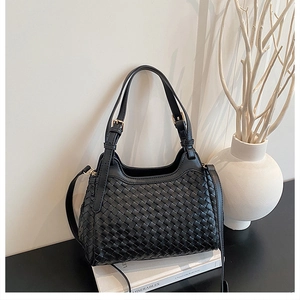 Détail de la texture tressée noire avec ferrures dorées et doubles poignées élégantes du sac