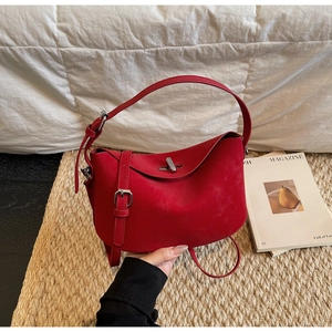Detail of red suede dumpling bag with crescent bottom and silver metal turn-lock
