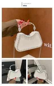 Detail of white half-moon bag with silver studs and spiral textured metal handle