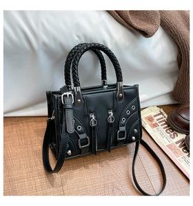 Detail view of black motorcycle bag featuring braided handles and punk metal stud accents