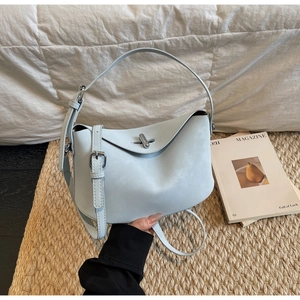 Detail of light blue crossbody bag featuring a silver metal fastener and adjustable strap