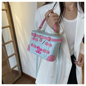 Detail of blue and pink box-shaped handbag with cartoon bunny and gold metal buckle