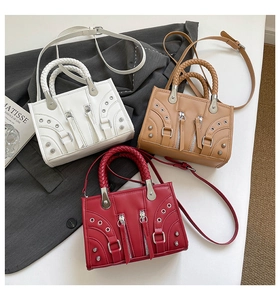 Close-up of three biker style handbags in white, brown, and red with woven handles