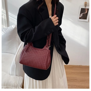 Détail d'un sac bandoulière tressé bordeaux avec tissage en cuir et bandoulière réglable
