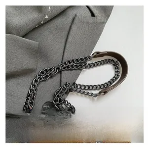 Detail of brown leather handbag featuring dark grey chain strap and pebble texture leather