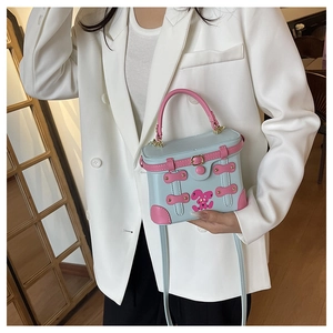 Detail of light blue box bag with pink handles and cartoon rabbit motif on model