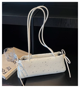 Close-up of white shoulder bag featuring silver star patterns and decorative bow tassels