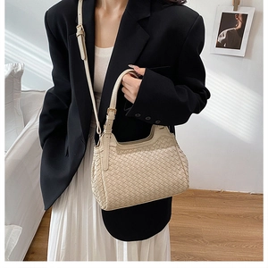 Détail macro du sac seau beige en cuir tressé avec boucle métallique chic sur la bandoulière