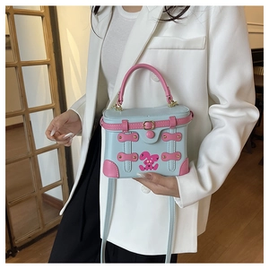 Detail of blue box bag with pink rabbit print and metal buckle on wooden floor