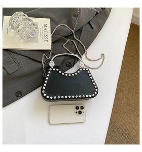 Detail of black leather box bag with silver studs and metal handle on artistic background