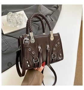 Detail of dark brown retro motorcycle bag with woven handles and silver stud hardware