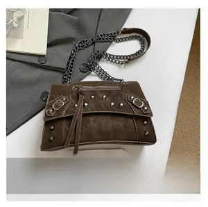 Detail of dark brown vintage faux leather bag with silver rivets and metallic chain strap
