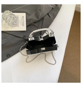 Detail of open black box bag with silver metal handle and interior view showing capacity