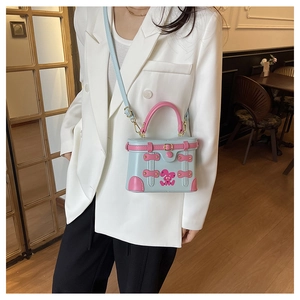Detail of a blue and pink contrast box bag featuring a cute cartoon rabbit and gold buckle