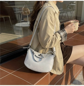 Detail of light grey retro crossbody bag featuring a classic lock and smooth leather texture