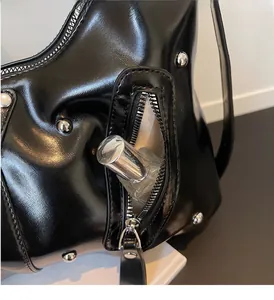 Detail der äußeren Reißverschlusstasche an einer schwarzen Nietenhandtasche im Punk-Stil