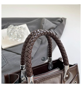 Macro detail of the dark brown leather handbag featuring a stylish woven top handle