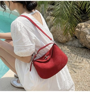 Deep red matte suede handbag with silver turn-lock clasp shown by the poolside