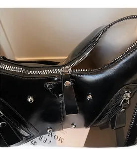Details silberner Nieten und glattem Reißverschluss an schwarzer Leder-Schultertasche