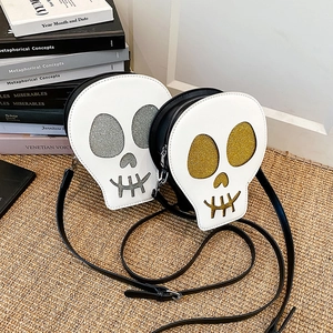 Unique skull-shaped crossbody bag with glitter eyes and black leather strap on a rustic background