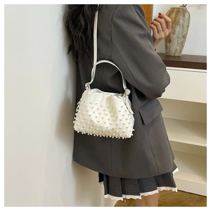 Dettaglio borsa a mano bianca con perle e trama litchi indossata da una modella