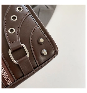 Close-up of dark brown leather handbag with silver rivets and buckle details