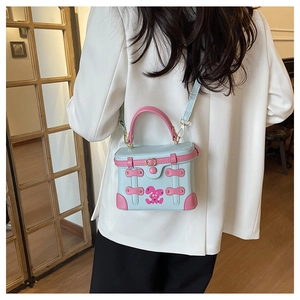 Detail of light blue box bag with pink handle and cartoon rabbit worn by a model