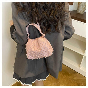 Modella che indossa una borsa a nuvola rosa chiaro con perle e trama a pieghe