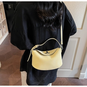 Detail view of the yellow hobo bag with a silver metal swivel clasp and leather texture