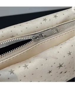 Detail of silver star hardware and smooth metal zipper on cream underarm bowling bag