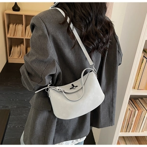 Close-up of a blue Lindy style crossbody bag with silver turn-lock on a grey blazer