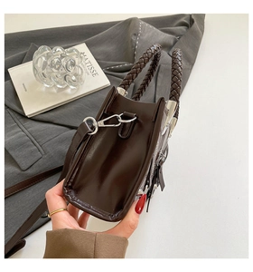 Close-up of the dark brown leather motorcycle bag with braided handle and silver hardware