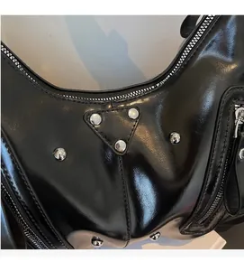 Detailansicht der schwarzen Lackledertasche mit Silbernieten und Metall-Dreiecksplatte