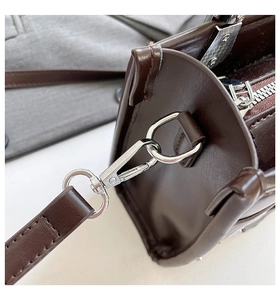 Macro view of silver metal hook and smooth dark brown leather on chic motorcycle bag