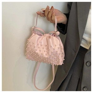 Dettaglio di una borsa a nuvola rosa con perle, portata da una modella in abito grigio
