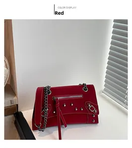 Detail of red matte leather handbag featuring silver studs, tassels and chain strap