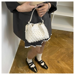 Dettaglio di una borsa a secchiello bianca con coulisse decorata con perle e manico