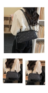 Detail of black underarm bag featuring white star prints and side drawstring details