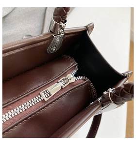 Macro view of interior zipper compartment and woven handle with silver hardware