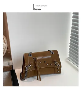 Detail view of brown vintage motorcycle bag with metal studs and chain strap