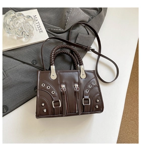 Macro view of dark brown leather handbag with woven handle and metallic zipper details