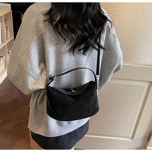 Close-up of black matte leather dumpling bag with silver metal swivel lock and strap
