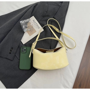 Flat lay of a pale yellow leather hobo bag with adjustable strap and silver hardware